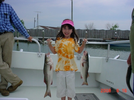 A young lady poses with her catch of the day. Two beautiful Maryland rockfish caught in June!